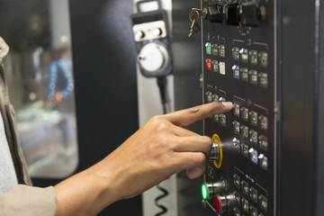 worker controls cnc machine at panel control