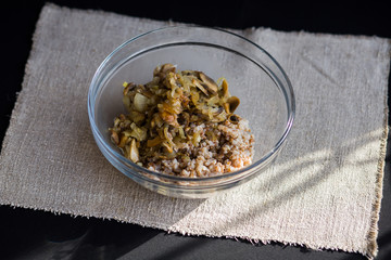 Buckwheat porridge with stewed mushrooms and onions in a plate on the table