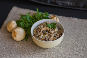 Buckwheat porridge with stewed mushrooms and onions in a plate on the table