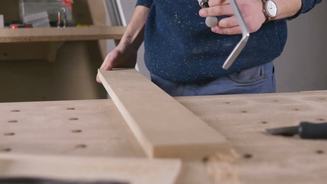 Young man working as carpenter and measuring board