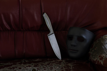 A sharp knife and a black mask on an old couch in an abandoned building. Dangerous conceptual.