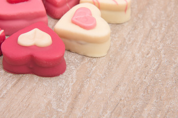 Close up of heart shaped petit fours cakes seen the side on a wooden background