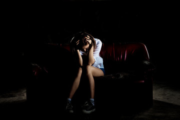 Unhappy lonely depressed woman sitting on old couch and contemplating suicide, in scary abandoned building, Concept of unemployed, sadness, depression, broken heart and human problem in dark tone.