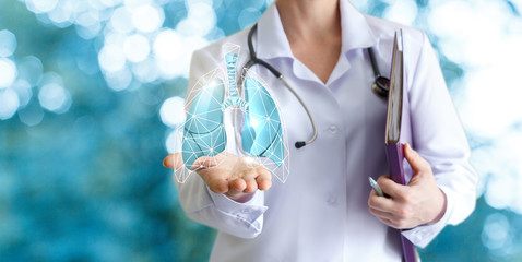 Doctor shows human lungs on blurred background.