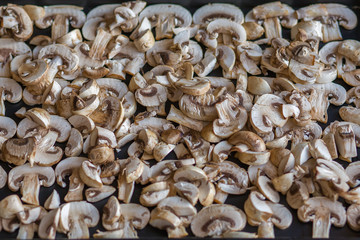 champignon mushrooms raw sliced slices on a table on a black background
