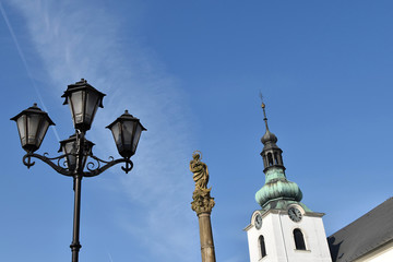 Fototapeta na wymiar Marian Plague Column and church in Svitavy, decorative street lamp