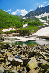  Mountain Lake with clean water and ice in the Caucasus summer. Blue sky with white clouds.