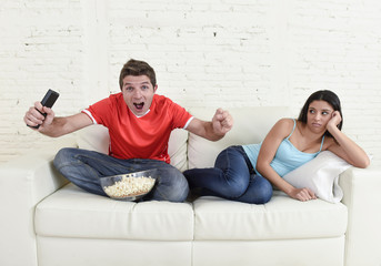  couple watching tv sport football with man excited celebrating crazy happy goal and woman bored