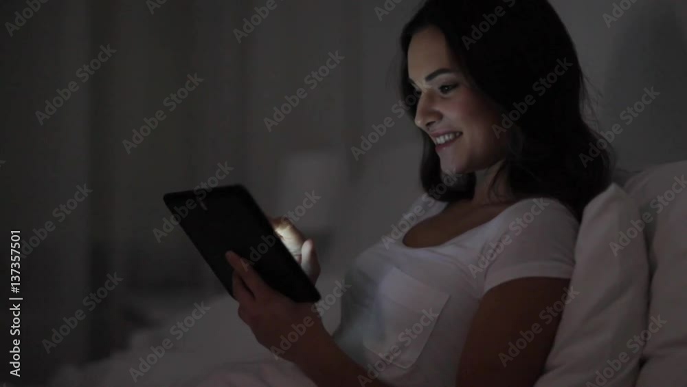 Poster young woman with tablet pc in bed at home bedroom