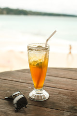 ice tea and glasses on wooden table at beach