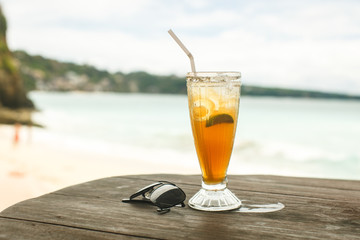 ice tea and glasses on wooden table at beach