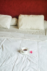 cup of tea and flower on white bed