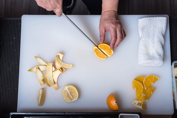 Bartender skillfully  cutting and peeling oranges and lemons on white board, top view