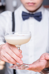 Bartender handing over cocktail with both hands, with foam, pale dogwood pink