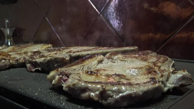 4k, cheff is cooking a Steak in hot Griddle of a kichen, T-bone steak is low fat healthy living meal choice -Dan