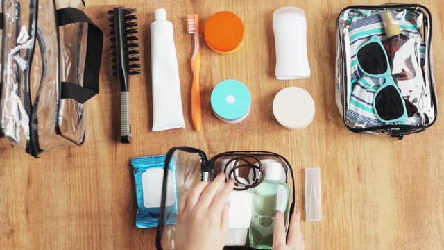 hands packing cosmetic bag with stuff for travel