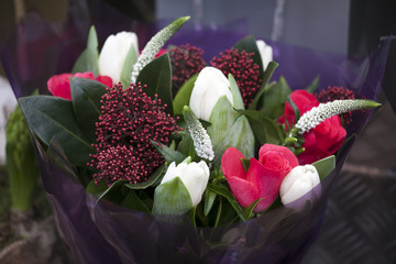 A close-up of bouquet of flowers. White and red tulips, white Veronica [Hebe], green juniper