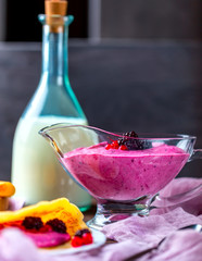 Sauceboat with curd cream and berries on a dark table