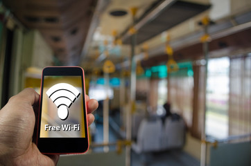 Hand using Smartphone and is using free wifi, Wifi Free on Bus concept on blurred background of people in public transportation bus, color tone effect.