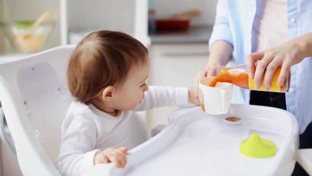 happy mother with spoon feeding baby at home