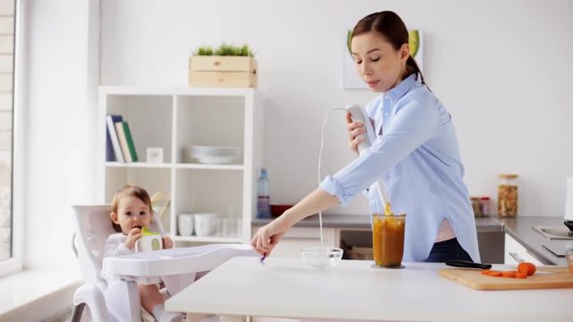mother with blender cooking baby food at home