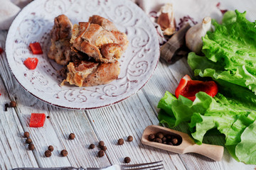 charcuterie, meat, baked pork rolls with egg omelet, Bulgarian red pepper, spice and lettuce on a wooden white background 