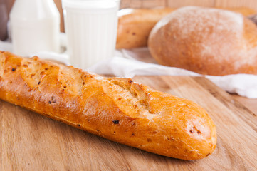 Close up baguette and assortment of breads and glass of milk on the background . Selective focus