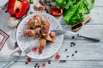 charcuterie, meat, baked pork rolls with egg omelet, Bulgarian red pepper, spice and lettuce on a wooden white background 