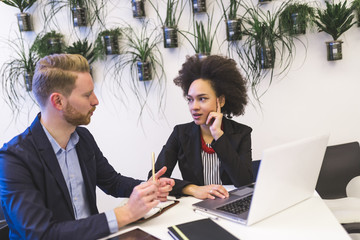 Multiracial confident business people working together connected with technological devices like tablet and notebook - teamwork, business, working concept 