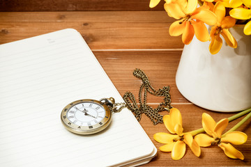 vintage pocket watch with yellow gardenia flower on wooden background