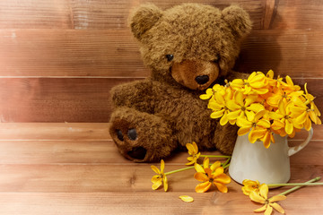 Teddy bear with a yellow bouquet of flowers with copy space