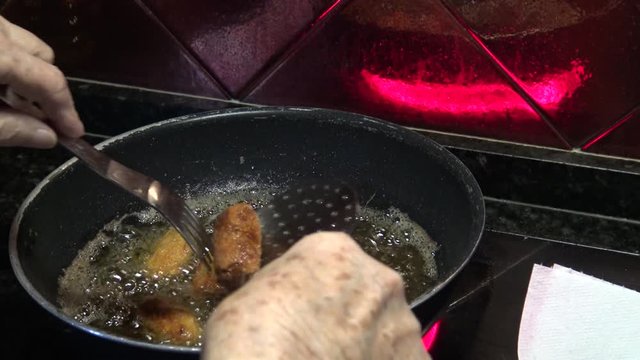 4k, Spanish Grandmather is cooking a cylindrical croquettes in hot pan with olive oil of a kichen. Croquette is a small breadcrumbed fried food roll containing main ingredients ground meat -Dan