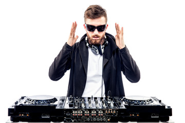 Young stylish man in black sunglasses posing with hands up behind mixing console on white studio...