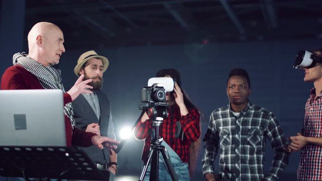 Director showing the video making process with camera and vr headset. Diverse multi ethnic students group. Close shot moving around camera. Stabilized movement shot