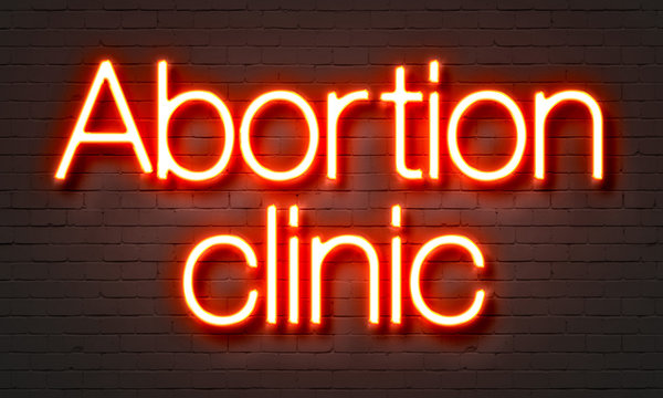 Abortion clinic neon sign on brick wall background.