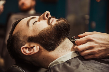 Professional Master hairdresser cuts client beard.