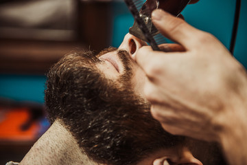 Professional Master hairdresser cuts client beard.