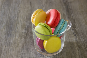 Colorful macaroons on gray wooden table. Sweet macarons in a glass cup. With copy space for your text