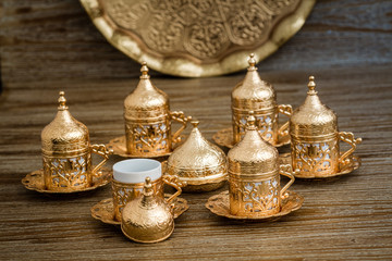 Fototapeta na wymiar Traditional Golden Coffee Cup Set in a Tray on Wooden Background