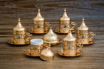 Fototapeta na wymiar Traditional Golden Coffee Cup Set in a Tray on Wooden Background