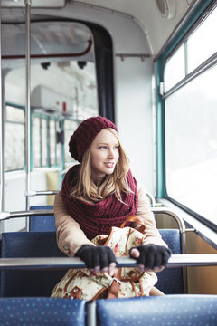 Beautiful young woman sitting in tram and looking through window. 