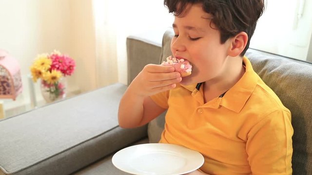 Portrait of a cute kid boy eating sweet donuts