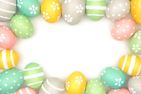 Frame of hand painted pastel Easter eggs over a white background