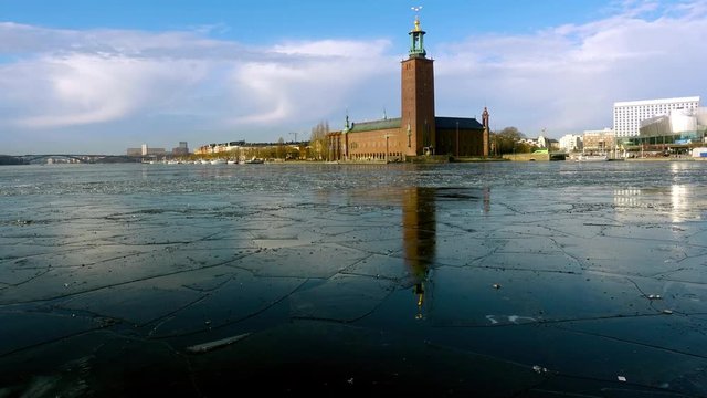 Time lapse of a ferry passing in front of the City Hall in Stockholm in wintry condition with ice floes covering the bay Riddarfjarden,