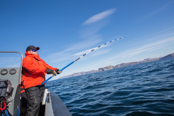 man pulls a fish out of water. Red Jacket. sports glasses. fisherman