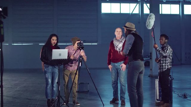 A group of people shooting a video blog in a studio hangar.