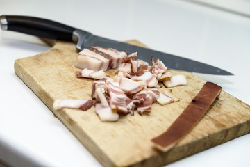 Thin cut bacon on a wooden board with a knife