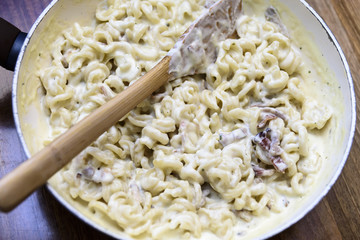 Preparing pasta with bacon and cheese
