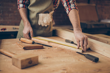 closeup photo of  cabinetmaker's tabletop.  Craftsman holding ruler  on wooden planknear other tools