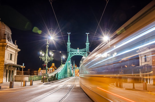 Night view of tram on Liberty Bridge or Freedom Bridge with lens flares in Budapest, Hungary